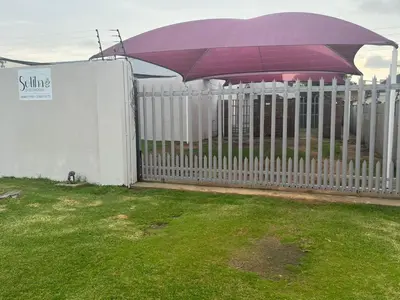 a white fence with an umbrella on top of it at Soliha Guesthouse in Trichardt