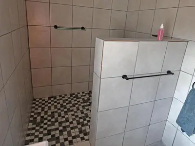 a bathroom with a shower with a tiled wall at Soliha Guesthouse in Trichardt