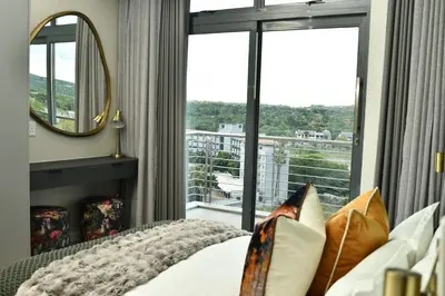 a bedroom with a bed and a large window at Apartment in Menlyn Maine, The Capital Trilogy in Pretoria