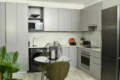 a kitchen with white cabinets and a table with chairs at Apartment in Menlyn Maine, The Capital Trilogy in Pretoria