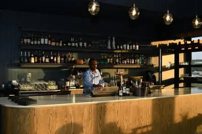 a man standing behind a bar in a room at Apartment in Menlyn Maine, The Capital Trilogy in Pretoria