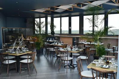 a restaurant with wooden tables and chairs and windows at Apartment in Menlyn Maine, The Capital Trilogy in Pretoria