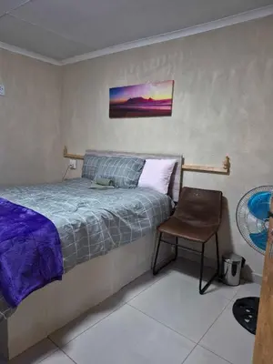a bedroom with a bed and a chair at Nare Guesthouse in Soshanguve