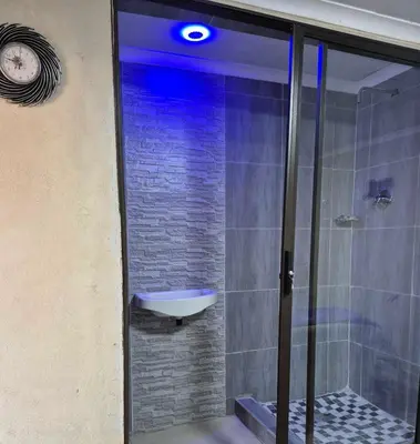 a bathroom with a walk in shower with a glass door at Nare Guesthouse in Soshanguve