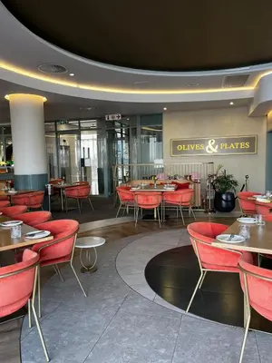 a dining room with red chairs and tables at Elegant Ellipse Waterfall Luxury with Gym, Spa & Dining in Midrand