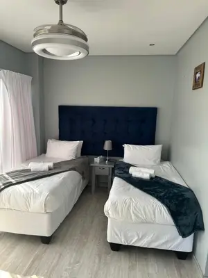 two beds in a bedroom with a blue headboard at Kbros Guesthouse in Polokwane