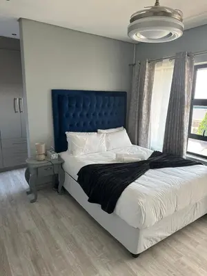 a bedroom with a large bed with a blue headboard at Kbros Guesthouse in Polokwane