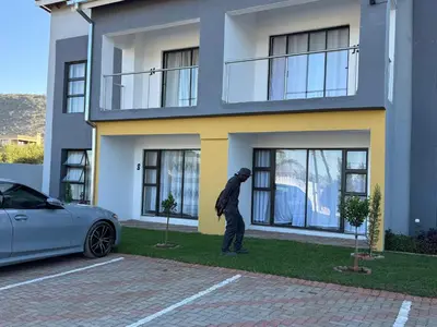 a man standing in front of a house with a car at KLAAK hotel and Apartments