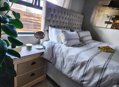 a bedroom with a bed and a table and a window at Cozy Corner in Midrand