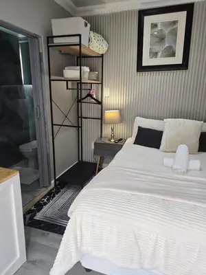 a bedroom with a bed and a shelf with towels at Cozy Cove Midrand in Midrand