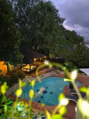 a large swimming pool in a yard with trees at Cozy Cove Midrand in Midrand