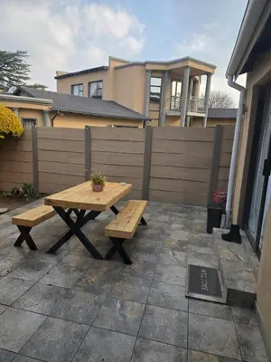 a wooden picnic table and bench in a backyard at Cozy Cove Midrand in Midrand