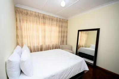 a bedroom with a white bed and a mirror at Airport Lodge Hotel in Kempton Park