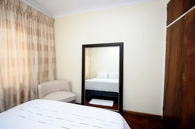 a bedroom with a mirror and a bed and a chair at Airport Lodge Hotel in Kempton Park