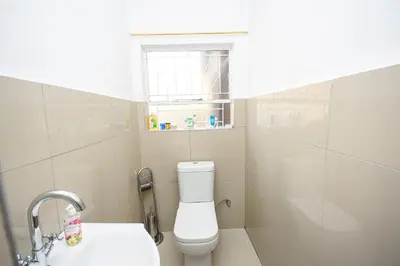 a bathroom with a toilet and a sink and a window at Airport Lodge Hotel in Kempton Park