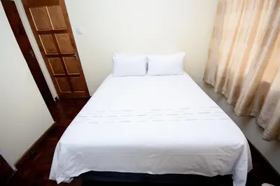 a white bed in a room with a window at Airport Lodge Hotel in Kempton Park