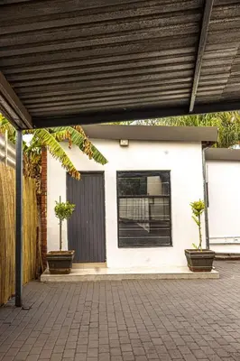 a white house with two potted plants on a patio at Thorne's crip in Pretoria