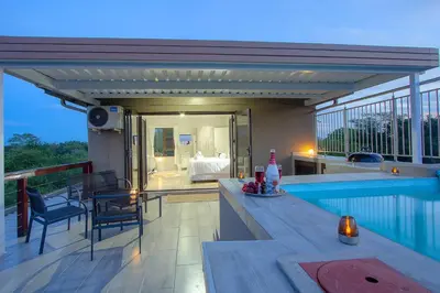 a balcony with a swimming pool and a bedroom at Penthouse At Kruger Safari Lodge in Marloth Park