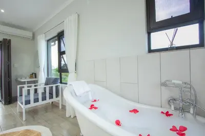 a bathroom with a tub with red flowers on it at Penthouse At Kruger Safari Lodge in Marloth Park