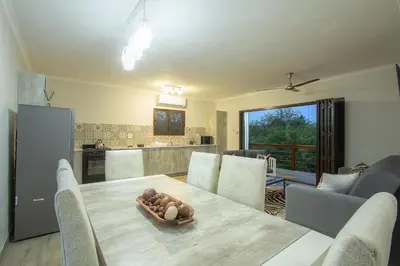 a kitchen and dining room with a table and chairs at Penthouse At Kruger Safari Lodge in Marloth Park