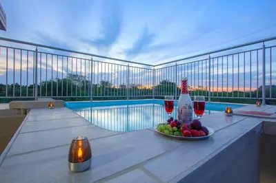 a table with a bowl of fruit and a bottle of wine at Penthouse At Kruger Safari Lodge in Marloth Park