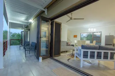 a living room with sliding glass doors and a couch at Penthouse At Kruger Safari Lodge in Marloth Park