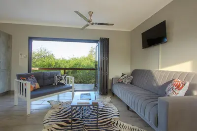 a living room with a couch and a tv at Penthouse At Kruger Safari Lodge in Marloth Park