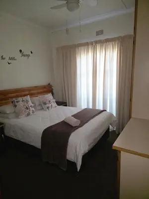 a bedroom with a large bed with a window at Lekker Breek Gastehuis in Groblersdal