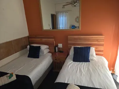 a bedroom with two beds and a mirror at Lekker Breek Gastehuis in Groblersdal
