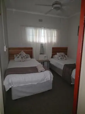 a bedroom with two beds and a window at Lekker Breek Gastehuis in Groblersdal