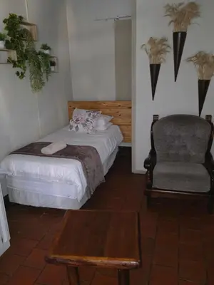 a bedroom with a bed and a chair and a table at Lekker Breek Gastehuis in Groblersdal