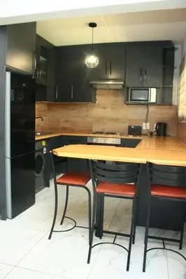 a kitchen with a wooden table and two bar stools at Unit 35 Pendleberry grove holidays in Bela-Bela