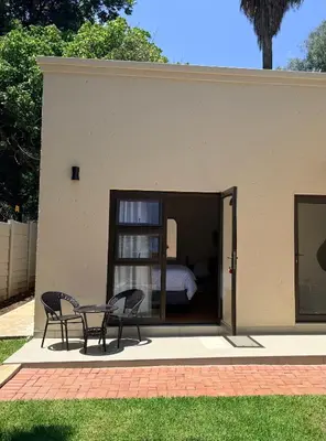 a patio with two chairs and a table in front of a house at Cathy & P Guesthouse in Hartbeespoort