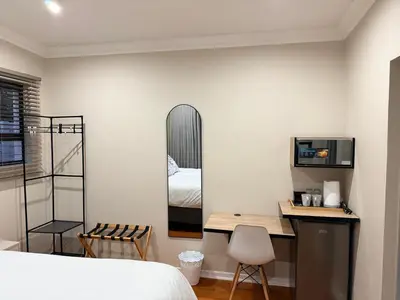 a bedroom with a bed and a desk and a mirror at Cathy & P Guesthouse in Hartbeespoort