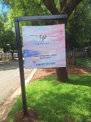 a sign in the grass next to a tree at Cathy & P Guesthouse in Hartbeespoort