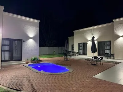 a patio with a blue swimming pool at night at Cathy & P Guesthouse in Hartbeespoort