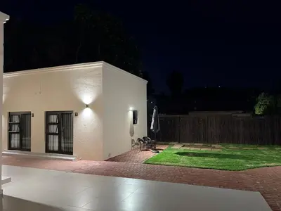a white building with a patio at night at Cathy & P Guesthouse in Hartbeespoort