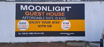 a sign for a guest house on a wall at Moonlight Guest House Lethabong in Vaalkop Dam