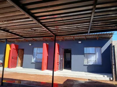 a blue building with red and yellow doors on it at Moonlight Guest House Lethabong in Vaalkop Dam