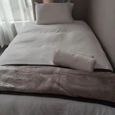 a bed with white sheets and pillows on it at Cozzy home in Polokwane