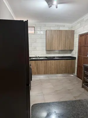 a kitchen with a black refrigerator and wooden cabinets at Cozzy home in Polokwane