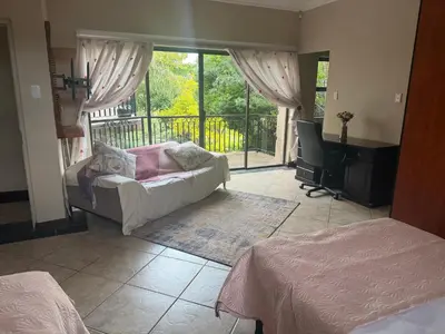 a bedroom with two beds and a desk and a balcony at The Country Hole Haven in Centurion