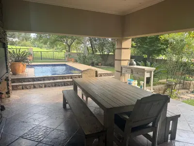 a patio with a wooden table and chairs and a pool at The Country Hole Haven in Centurion