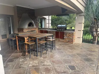 an outdoor kitchen with a table and chairs and a grill at The Country Hole Haven in Centurion