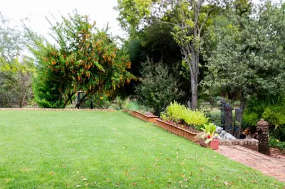 a garden with a lawn and some bushes and trees at Buchan's Corner Unit 2 in Hartbeespoort
