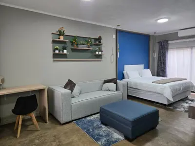 a bedroom with a bed and a couch and a bed and a table at Cuse Boutique Lodge and Conference in Polokwane