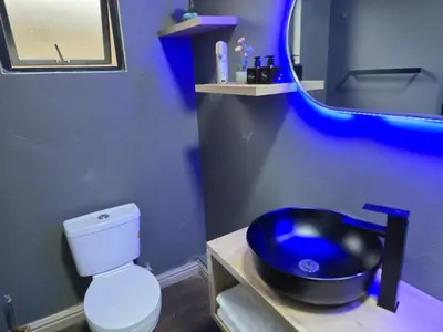 a blue bathroom with a sink and a toilet at Cuse Boutique Lodge and Conference in Polokwane
