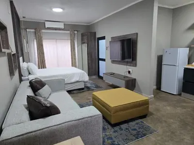 a living room with a couch and a bed at Cuse Boutique Lodge and Conference in Polokwane