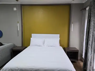 a bedroom with a large white bed with a yellow wall at Cuse Boutique Lodge and Conference in Polokwane