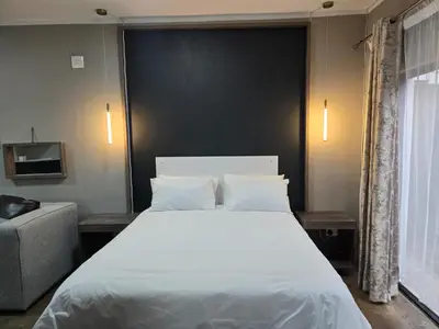 a bedroom with a large white bed and a couch at Cuse Boutique Lodge and Conference in Polokwane